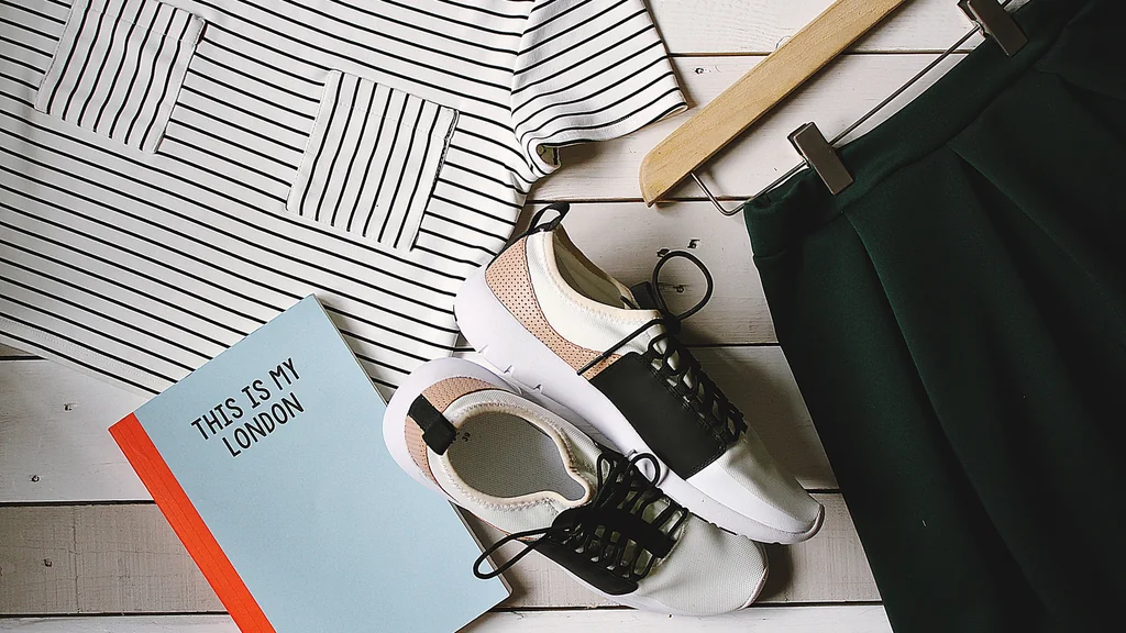 Abiti, scarpe e un quaderno disposti in flat lay su una superficie chiara