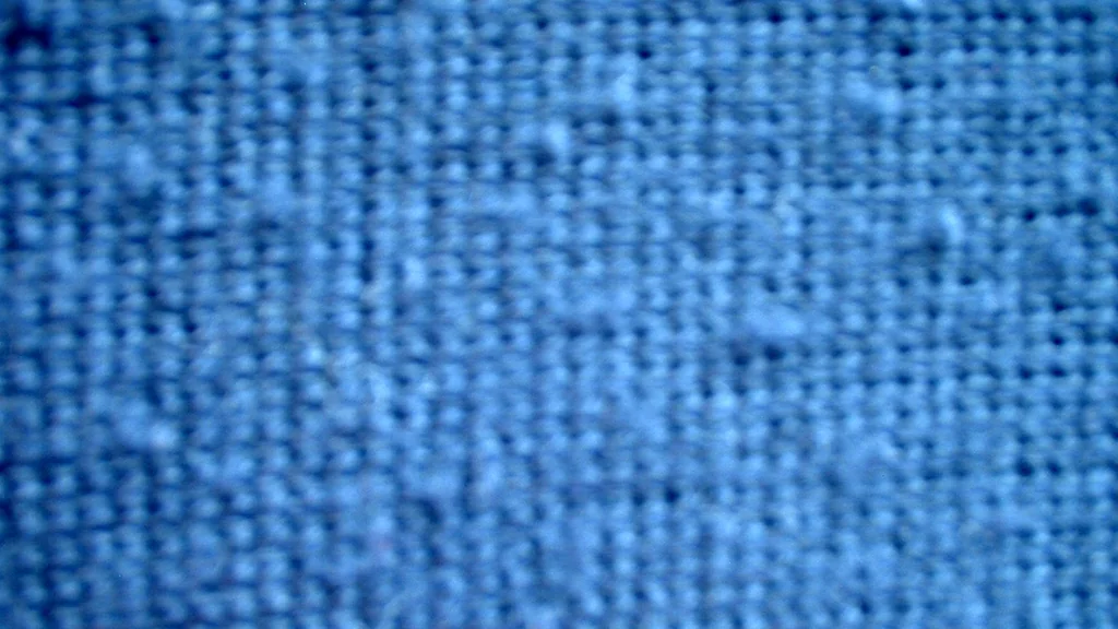Primo piano di tessuto a maglia blu con piccoli pallini di fibre sulla superficie